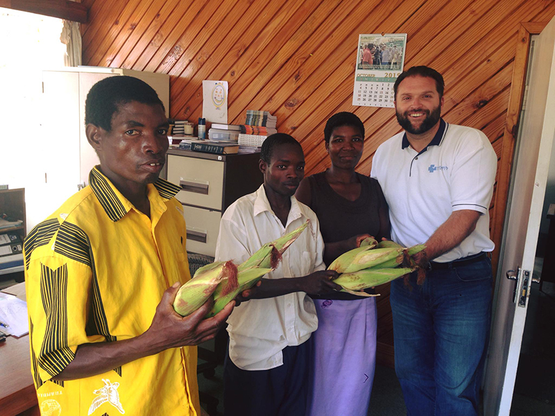 3 men and 1 woman holding corn with husks