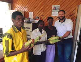 3 men and 1 woman holding corn with husks