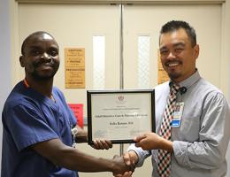 Derek Hidalgo, MBA, RN, BSN, director of patient care MICU/SICU/Neurology, right, presents Felix Batson, RN with a mentorship program certificate.